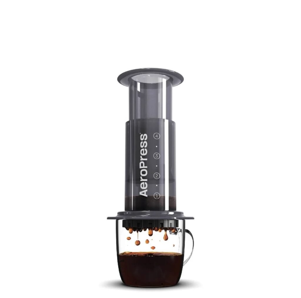 AeroPress coffee maker on white background, brewing into a glass mug